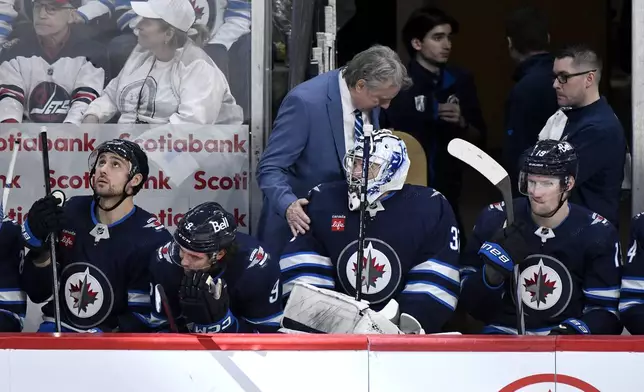 Winnipeg Jets coach Rick Bowness speaks with goaltender Connor Hellebuyck (37) after he was pulled for the extra attacker against the Colorado Avalanche during the third period in Game 2 of an NHL hockey Stanley Cup first-round playoff series Tuesday, April 23, 2024, in Winnipeg, Manitoba. (Fred Greenslade/The Canadian Press via AP)