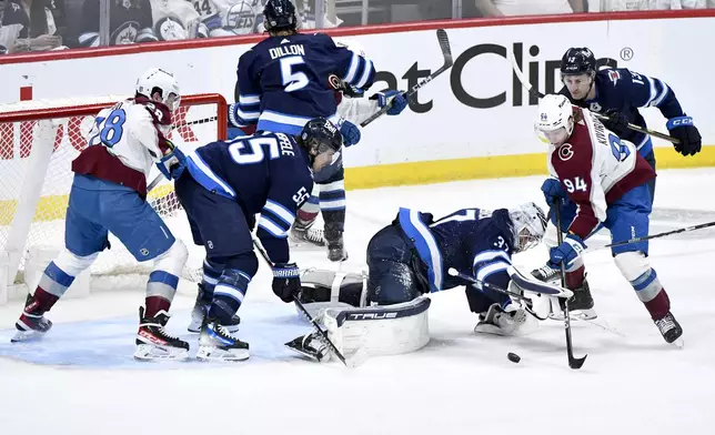 Colorado Avalanche's Joel Kiviranta (94) looks for the loose puck in front of Winnipeg Jets goaltender Connor Hellebuyck (37) during the second period in Game 2 of an NHL hockey Stanley Cup first-round playoff series Tuesday, April 23, 2024, in Winnipeg, Manitoba. (Fred Greenslade/The Canadian Press via AP)