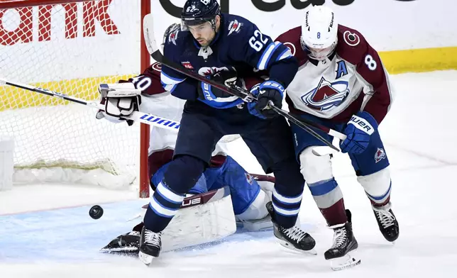 Colorado Avalanche's Cale Makar (8) and Winnipeg Jets' Nino Niederreiter (62) vie for a rebound during the third period in Game 2 of an NHL hockey Stanley Cup first-round playoff series Tuesday, April 23, 2024, in Winnipeg, Manitoba. (Fred Greenslade/The Canadian Press via AP)