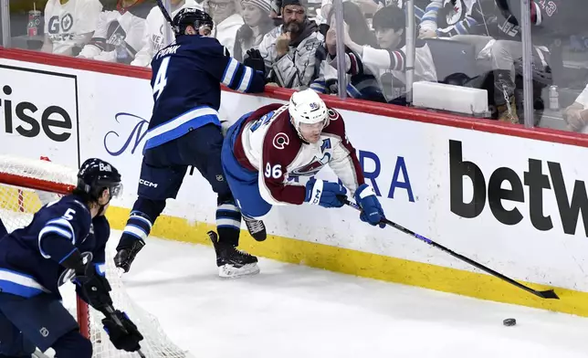 Colorado Avalanche's Mikko Rantanen (96) is tripped by Winnipeg Jets' Neal Pionk (4) during the third period in Game 2 of an NHL hockey Stanley Cup first-round playoff series Tuesday, April 23, 2024, in Winnipeg, Manitoba. (Fred Greenslade/The Canadian Press via AP)