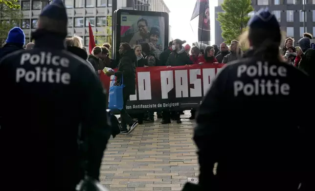 Police look on as demonstrators hold a banner outside the National Conservatism conference in Brussels, Tuesday, April 16, 2024. (AP Photo/Virginia Mayo)