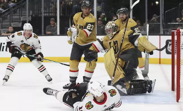 Chicago Blackhawks center Jason Dickinson (16) falls as Vegas Golden Knights goaltender Logan Thompson (36) makes a save during the first period of an NHL hockey game Tuesday, April 16, 2024, in Las Vegas. (AP Photo/Ian Maule)