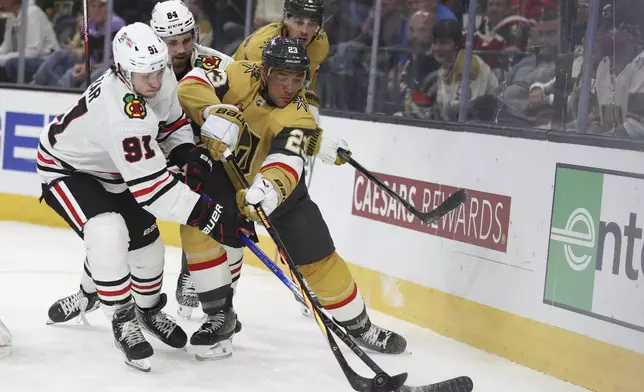 Chicago Blackhawks center Frank Nazar (91) attempts to steal the puck from Vegas Golden Knights defenseman Alec Martinez (23) during the third period of an NHL hockey game Tuesday, April 16, 2024, in Las Vegas. (AP Photo/Ian Maule)