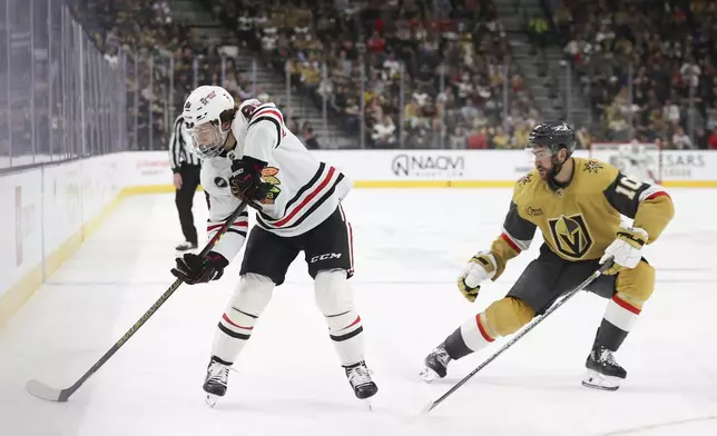 Chicago Blackhawks center Connor Bedard (98) passes around Vegas Golden Knights center Nicolas Roy (10) during the first period of an NHL hockey game Tuesday, April 16, 2024, in Las Vegas. (AP Photo/Ian Maule)
