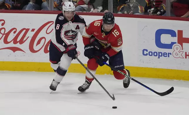 Columbus Blue Jackets defenseman Zach Werenski (8) and Florida Panthers center Aleksander Barkov (16) go after the puck during the first period of an NHL hockey game, Thursday, April 11, 2024, in Sunrise, Fla. (AP Photo/Marta Lavandier)