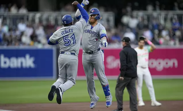 Toronto Blue Jays designated hitter Justin Turner, center, celebrates with third base coach Carlos Febles (51) after hitting a home run during the first inning of a baseball game against the San Diego Padres, Friday, April 19, 2024, in San Diego. (AP Photo/Gregory Bull)