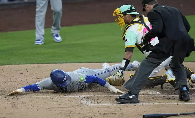 Toronto Blue Jays' Cavan Biggio, left, slides in to score off a two-RBI double by Kevin Kiermaier as San Diego Padres catcher Kyle Higashioka, center, is late with the tag during the second inning of a baseball game, Friday, April 19, 2024, in San Diego. (AP Photo/Gregory Bull)