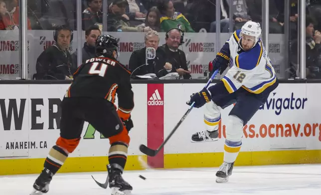 St. Louis Blues right wing Keven Hayes (12) passes the puck as Anaheim Ducks defensemen Cam Fowler (4) defends during the second period of an NHL hockey game Sunday, April 7, 2024, in Anaheim, Calif. (AP Photo/Yannick Peterhans)