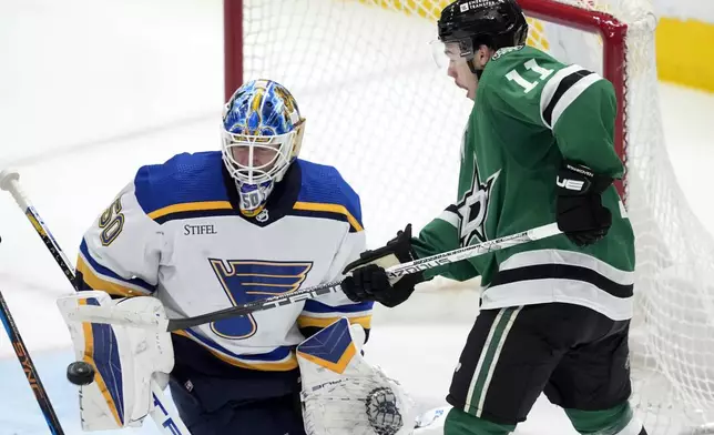 St. Louis Blues goaltender Jordan Binnington (50) deflects a shot with his arm pad under pressure from Dallas Stars center Logan Stankoven (11) during the second period of an NHL hockey game in Dallas, Wednesday, April 17, 2024. (AP Photo/Tony Gutierrez)
