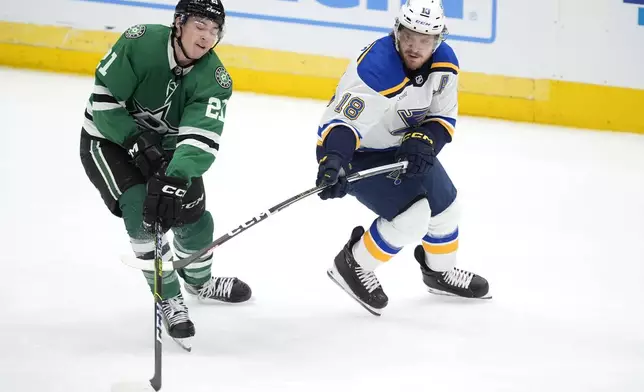 Dallas Stars left wing Jason Robertson (21) looks to take control of the puck in front of St. Louis Blues center Robert Thomas (18) in the third period of an NHL hockey game in Dallas, Wednesday, April 17, 2024. (AP Photo/Tony Gutierrez)