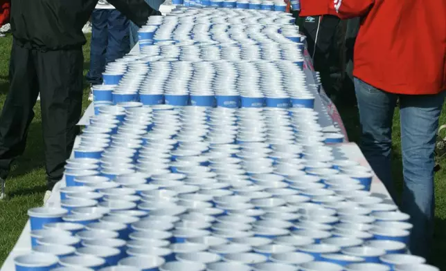 FILE - Runners pick up water in the athlete's village in Hopkinton, Mass. before the start of the Boston Marathon on Monday, April 19, 2004. Once a year for the last 100 years, Hopkinton becomes the center of the running world, thanks to a quirk of geography and history that made it the starting line for the world's oldest and most prestigious annual marathon. (AP Photo/Joe Giblin, File)