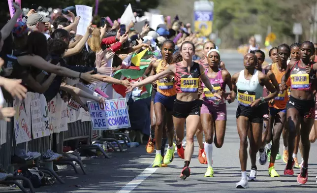 Emma Bates, center, gives high fives to spectators at Wellesley College as she and the other leaders of the women's division run through Wellesley, Mass., during the Boston Marathon, Monday, April 15, 2024. Bates was the top American finisher. (AP Photo/Jennifer McDermott)