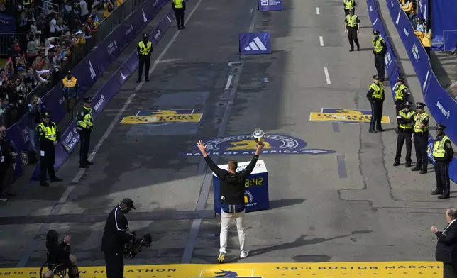 Former New England Patriots NFL football player Rob Gronkowski hoists the winner's trophy at the Boston Marathon, Monday, April 15, 2024, in Boston. Gronkowski is grand marshal of the race. (AP Photo/Charles Krupa)