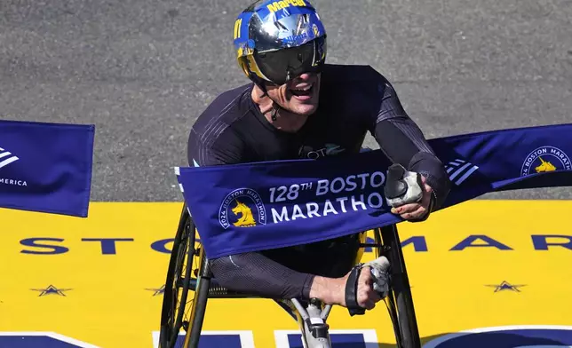 Marcel Hug of Switzerland breaks the tape to win the men's wheelchair division at the Boston Marathon, Monday, April 15, 2024, in Boston. (AP Photo/Charles Krupa)