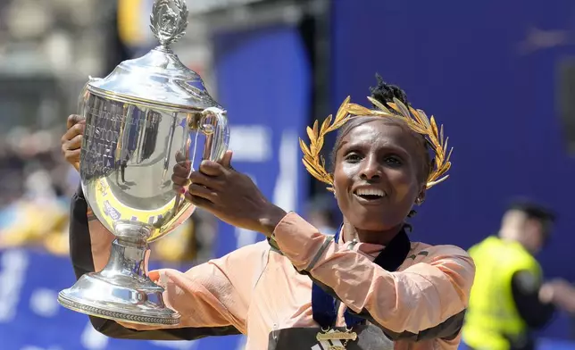 Hellen Obiri, of Kenya, displays the trophy on finish line after winning the women's division at the Boston Marathon, Monday, April 15, 2024, in Boston. (AP Photo/Steven Senne)