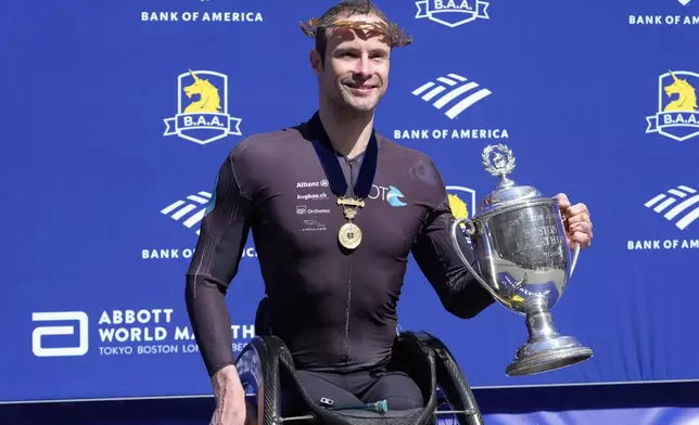 Boston Marathon men's wheelchair division winner Marcel Hug, of Switzerland, poses with the trophy after the race, Monday, April 15, 2024, in Boston. (AP Photo/Steven Senne)