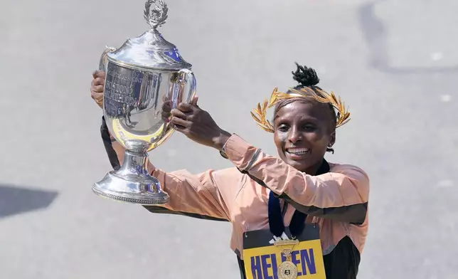 Hellen Obiri, of Kenya, raises the trophy after winning the women's division at the Boston Marathon, Monday, April 15, 2024, in Boston. (AP Photo/Charles Krupa)