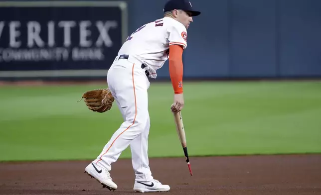 Houston Astros third baseman Alex Bregman picks up the barrel of Atlanta Braves' Ronald Acuña Jr. broken bat from the baseline during the first inning of a baseball game Tuesday, April 16, 2024, in Houston. (AP Photo/Michael Wyke)