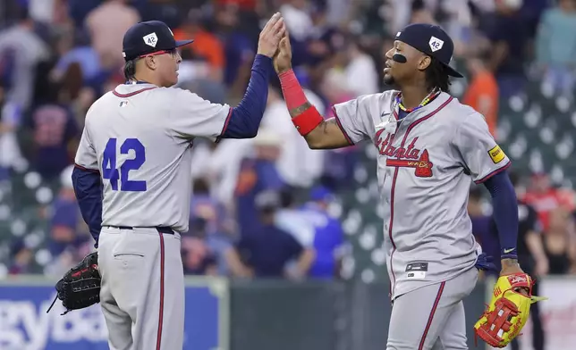 Atlanta Braves closing pitcher Jesse Chavez, left, high-fives right fielder Ronald Acuna Jr., right, after their win over the Houston Astros in a baseball game Monday, April 15, 2024, in Houston. All players wore No. 42 in honor of Jackie Robinson Day. (AP Photo/Michael Wyke)
