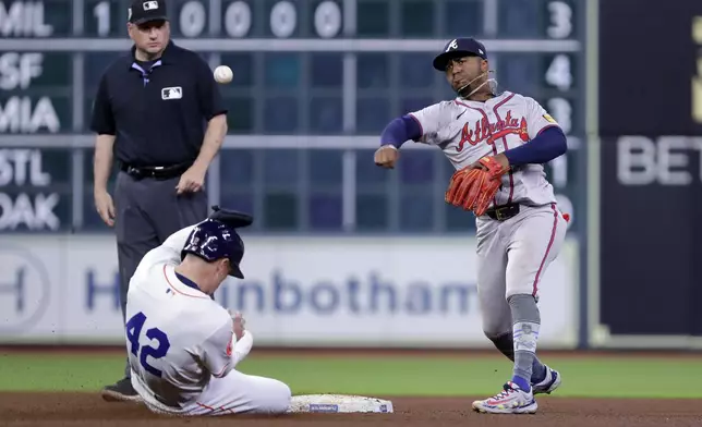 Houston Astros runner Alex Bregman, front left, is out on his slide as Atlanta Braves second baseman Ozzie Albies, right, throws over him while attempting to turn a double play during the sixth inning of a baseball game Monday, April 15, 2024, in Houston. (AP Photo/Michael Wyke)