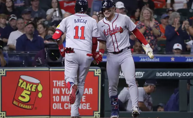 Atlanta Braves' Orlando Arcia (11) and Jarred Kelenic, right, celebrate Arcia's home run against the Houston Astros during the inning of a baseball game Tuesday, April 16, 2024, in Houston. (AP Photo/Michael Wyke)