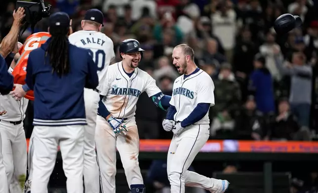 Seattle Mariners designated hitter Mitch Garver, right, throws his batting helmet as he celebrates hitting a two-run walk-off home run against the Atlanta Braves with teammates, including Cal Raleigh, second from right, in a baseball game Monday, April 29, 2024, in Seattle. (AP Photo/Lindsey Wasson)