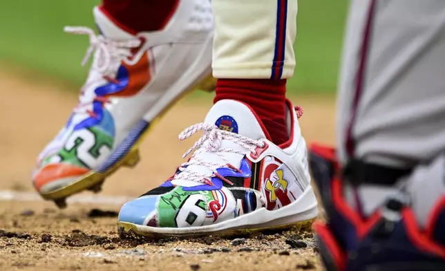 Philadelphia Phillies' Bryce Harper steps into the batters box during the first inning of a baseball game against the Atlanta Braves, Saturday, March 30, 2024, in Philadelphia. Former Philadelphia Eagle Jason Kelce autographed Harper's shoe after throwing out the first pitch. (AP Photo/Derik Hamilton)
