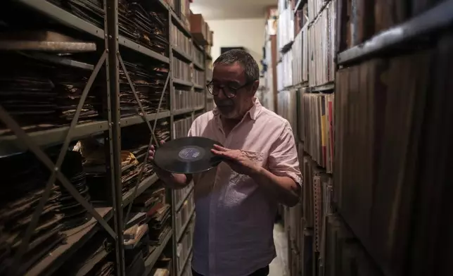 Carlos Savalla holds an album produced by the Brazilian record company RGE founded in 1947, in his studio where he maintains his music collection, in Rio de Janeiro, Brazil, Friday, April 19, 2024. Savalla, a 66-year-old music producer in Rio, owns more than 60,000 vinyl records. (AP Photo/Bruna Prado)