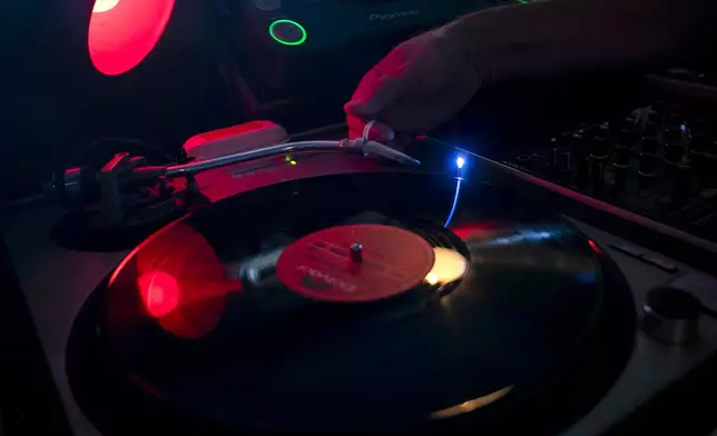 Deejay Mustafa Baba-Aissa, originally from Algeria, places a needle on a vinyl record on a turntable in his Vinil do Mustafa record shop, in Rio de Janeiro, Brazil, Friday, April 19, 2024. Vinyl records in Brazil outsold CDs and DVDs for the first time last year. (AP Photo/Bruna Prado)