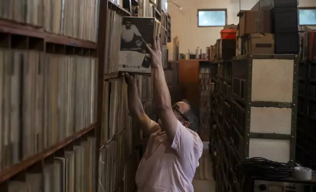 Carlos Savalla returns a batch of albums to a shelf in his studio where he maintains his music collection, in Rio de Janeiro, Brazil, Friday, April 19, 2024. Savalla, a 66-year-old music producer in Rio, owns more than 60,000 vinyl records. (AP Photo/Bruna Prado)