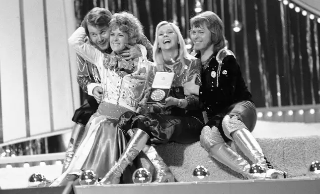 FILE - In this April 6, 1974 file photo, Swedish pop group ABBA celebrate winning the 1974 Eurovision Song Contest on stage at the Brighton Dome in England with their song Waterloo. Fans are celebrating 50 years since ABBA won its first big battle with “Waterloo.” A half century ago on Saturday, April 6, the Swedish quartet triumphed at the 1974 Eurovision Song Contest with the peppy love song. (AP Photo/Robert Dear, File)