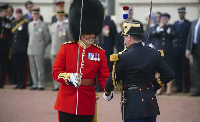 A member of the Scots Guards and a member of France's 1er Regiment de le Garde Republicaine shake hands as they partake in the Changing of the Guard ceremony at Buckingham Palace, to commemorate the 120th anniversary of the Entente Cordiale - the historic diplomatic agreement between Britain and France which laid the groundwork for their collaboration in both world wars, in London, Monday, April 8, 2024. France is the first non-Commonwealth country to take part in the Changing of the Guard. (Victoria Jones/Pool Photo via AP)