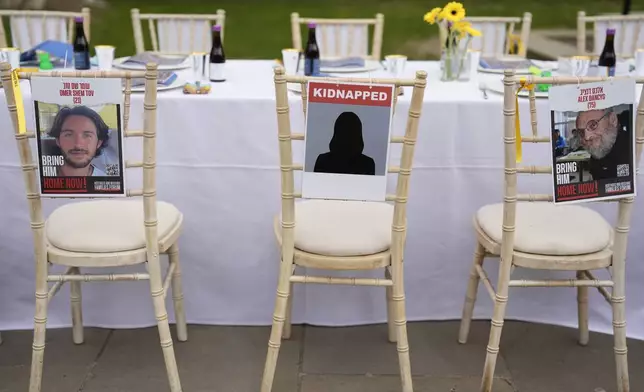 Chair with photos attached of people kidnapped from Israel by Hamas militant at "The Empty Seder Table' with 133 chairs and place settings representing the absence of hostages, in London, Wednesday, April 17, 2024. (AP Photo/Alastair Grant)