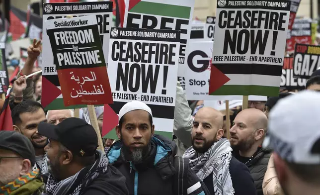 Pro-Palestinian protesters hold placards as they take part in a demonstration in London, Saturday, April 27, 2024. (AP Photo/Thomas Krych)