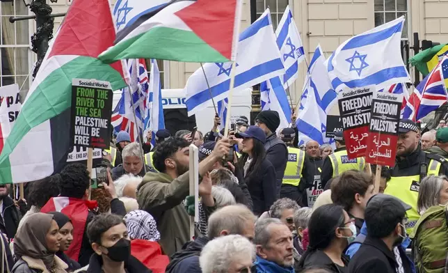 People take part in a pro-Palestine march as they walk past a counter protest with Israeli flags, at Waterloo Place in central London, Saturday, April 27, 2024. (Jeff Moore/PA via AP)