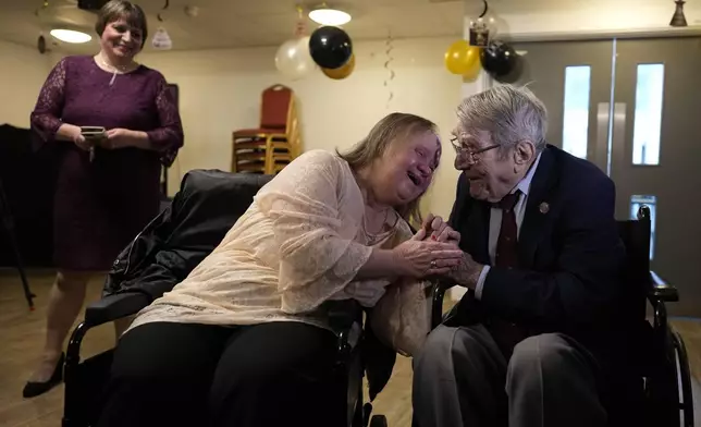 FILE - D-Day veteran Bill Gladden greets his tearful daughter Lynda, watched by his niece Kaye Thorpe at a surprise 100th birthday party in Haverhill, England, Friday, Jan. 12, 2024. Gladden, one of the dwindling number of veterans who took part in the landings that kicked off the campaign to liberate Western Europe from the Nazis during World War II, died Wednesday, April 24, 2024, his family said. He was 100. (AP Photo/Alastair Grant, File)