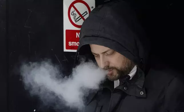 A man smokes on a street, in London, Tuesday, April 16, 2024. A bold plan to ban anyone born after 2008 from ever legally buying cigarettes in Britain faces its first test in Parliament. The bold plan has divided the governing Conservatives, with some hailing its public health benefits and others condemning it as state overreach. (AP Photo/Kin Cheung)
