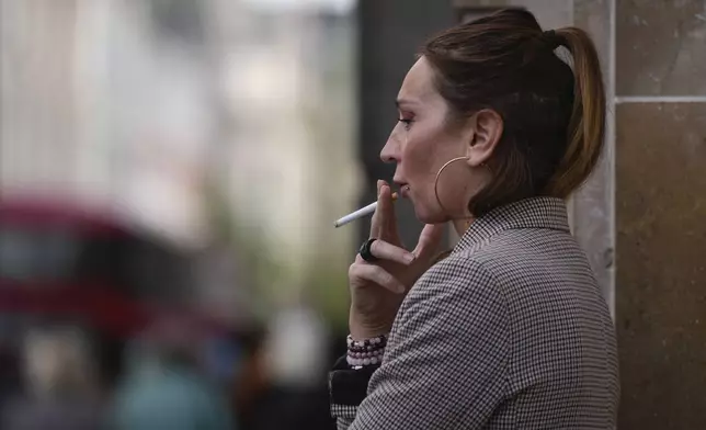 A woman smokes on a street, in London, Tuesday, April 16, 2024. A bold plan to ban anyone born after 2008 from ever legally buying cigarettes in Britain faces its first test in Parliament. The bold plan has divided the governing Conservatives, with some hailing its public health benefits and others condemning it as state overreach. (AP Photo/Kin Cheung)