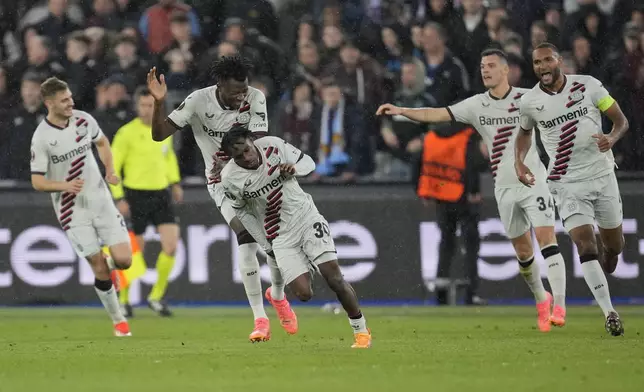 Leverkusen's Jeremie Frimpong, centre, celebrates after scoring his side's opening goal during the Europa League quarterfinal second leg soccer match between West Ham and Bayer 04 Leverkusen in London, Thursday, April 18, 2024.(AP Photo/Kin Cheung)