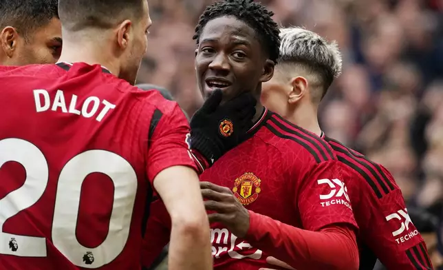 Manchester United's Kobbie Mainoo, centre, celebrates with teammates after scoring his side's second goal during the English Premier League soccer match between Manchester United and Liverpool at the Old Trafford stadium in Manchester, England, Sunday, April 7, 2024. (AP Photo/Dave Thompson)