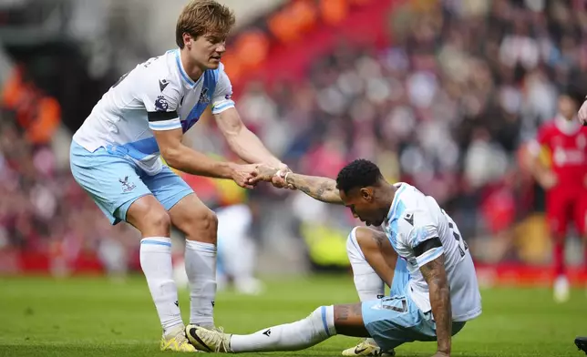 Crystal Palace's Joachim Andersen, left, helps to Crystal Palace's Nathaniel Clyne during the English Premier League soccer match between Liverpool and Crystal Palace at Anfield Stadium in Liverpool, England, Sunday, April 14, 2024. (AP Photo/Jon Super)