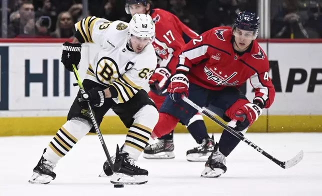 Boston Bruins left wing Brad Marchand (63) skates with the puck against Washington Capitals defenseman Martin Fehervary (42) during the first period of an NHL hockey game, Monday, April 15, 2024, in Washington. (AP Photo/Nick Wass)
