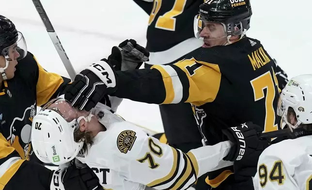 Pittsburgh Penguins' Evgeni Malkin (71) puts a glove to the face of Boston Bruins' Jesper Boqvist (70) during the first period of an NHL hockey game Saturday, April 13, 2024, in Pittsburgh. (AP Photo/Matt Freed)