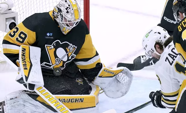 Pittsburgh Penguins goaltender Alex Nedeljkovic (39) makes a save against Boston Bruins' Pavel Zacha, right, during the first period of an NHL hockey game Saturday, April 13, 2024, in Pittsburgh. (AP Photo/Matt Freed)