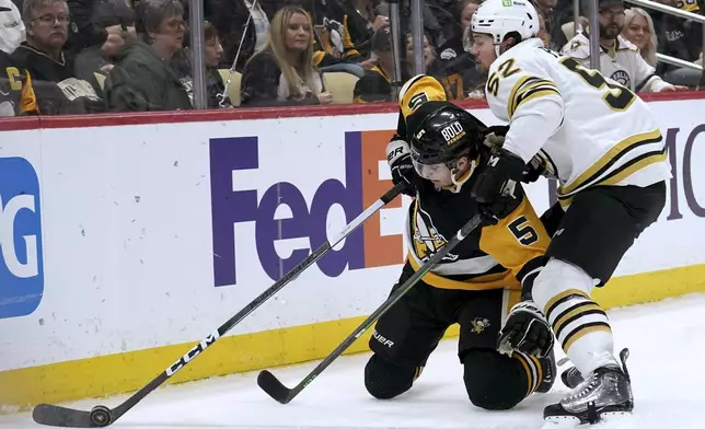 Pittsburgh Penguins' Ryan Shea (5) reaches for the puck as Boston Bruins' Andrew Peeke (52) defends during the second period of an NHL hockey game Saturday, April 13, 2024, in Pittsburgh. (AP Photo/Matt Freed)
