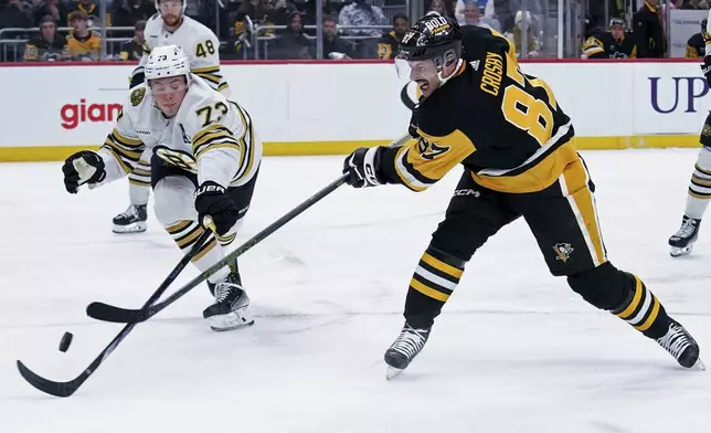 Pittsburgh Penguins' Sidney Crosby (87) shoots as Boston Bruins' Charlie McAvoy (73) defends during the second period of an NHL hockey game, Saturday, April 13, 2024, in Pittsburgh. (AP Photo/Matt Freed)