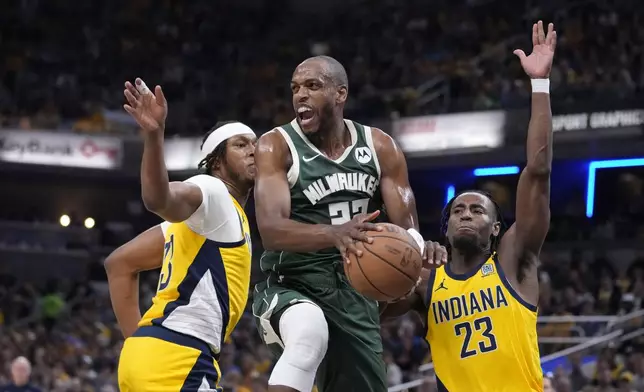 Milwaukee Bucks' Khris Middleton (22) makes a pass against Indiana Pacers' Myles Turner (33) and Aaron Nesmith (23) during the first half of Game 4 of the first round NBA playoff basketball series, Sunday, April 28, 2024, in Indianapolis. (AP Photo/Michael Conroy)