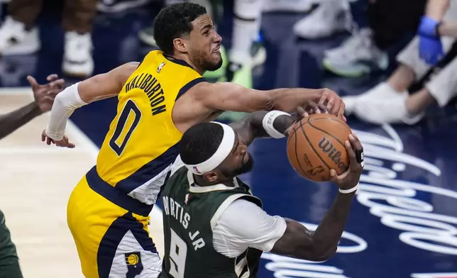 Milwaukee Bucks forward Bobby Portis (9) grabs a rebound behind Indiana Pacers guard Tyrese Haliburton (0) during the second half in Game 2 in an NBA basketball first-round playoff series, Friday, April 26, 2024, in Indianapolis. (AP Photo/Michael Conroy)