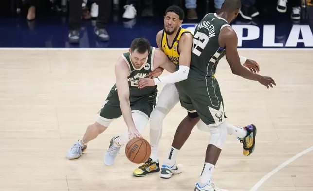 Milwaukee Bucks' Pat Connaughton (24) goes to the basket against Indiana Pacers' Tyrese Haliburton (0) as Khris Middleton sets a pick during the first half of Game 4 of the first round NBA playoff basketball series, Sunday, April 28, 2024, in Indianapolis. (AP Photo/Michael Conroy)