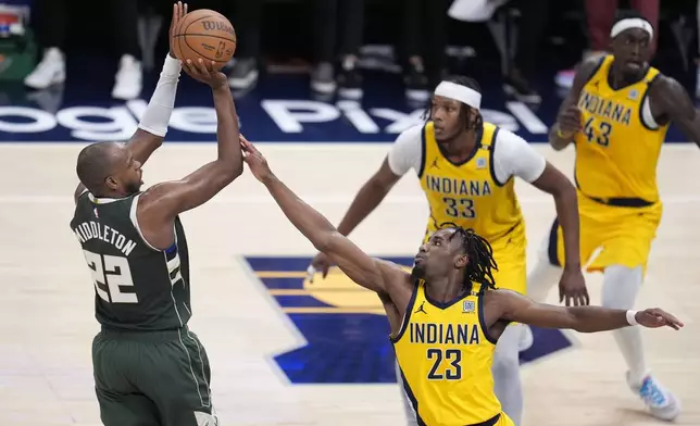Milwaukee Bucks' Khris Middleton (22) shoots over Indiana Pacers' Aaron Nesmith (23) during the first half of Game 4 of the first round NBA playoff basketball series, Sunday, April 28, 2024, in Indianapolis. (AP Photo/Michael Conroy)